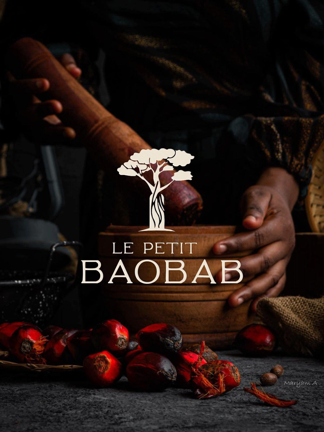Mains pilant au mortier, graines de palme rouges au premier plan, logo Le Petit Baobab